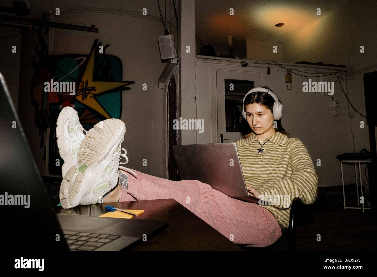 Pleine longueur de femme entrepreneur travaillant sur ordinateur portable avec les pieds sur la table au bureau Banque D'Images