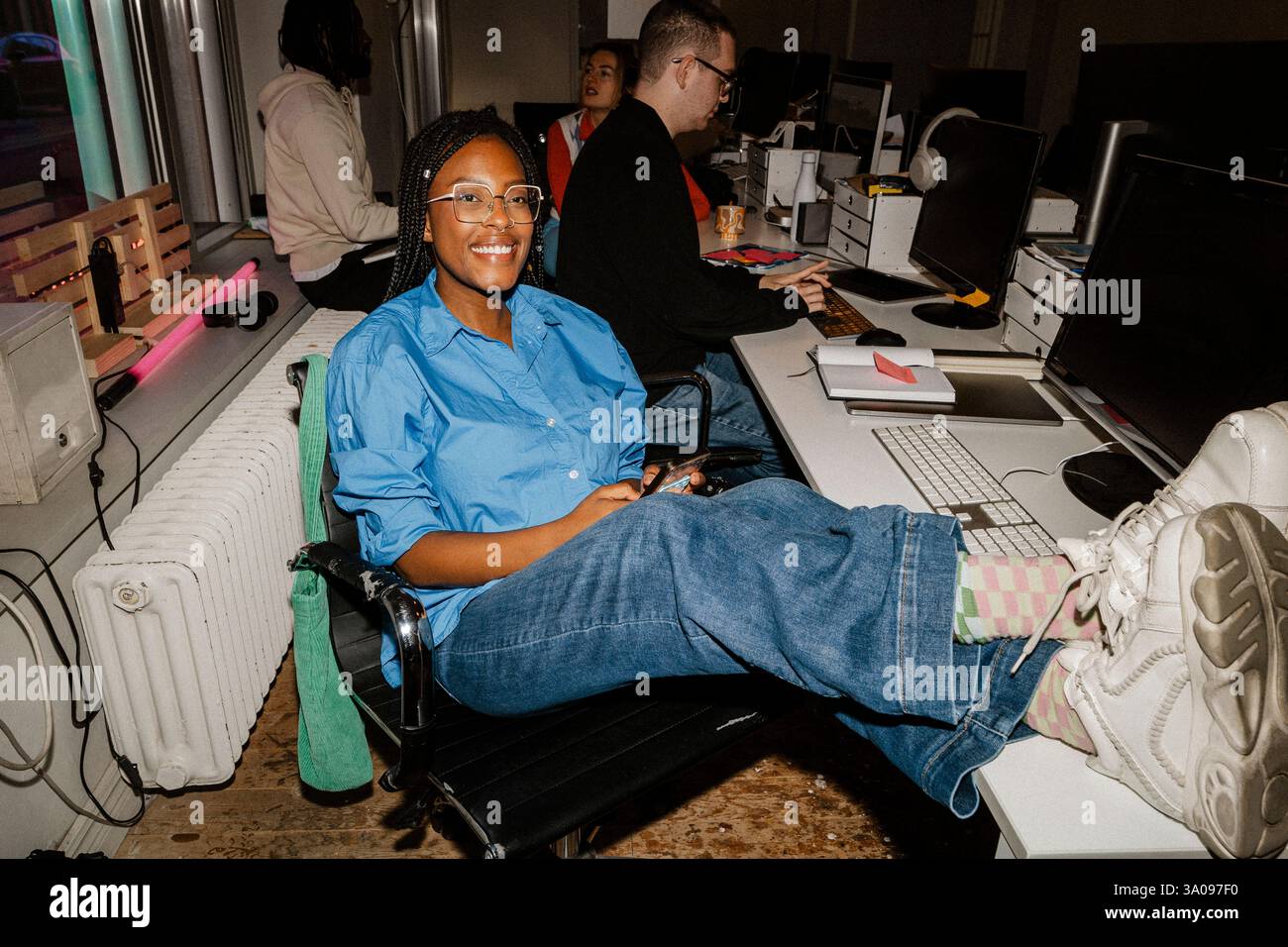 Portrait de femme entrepreneure souriante assise les pieds sur la table au bureau Banque D'Images