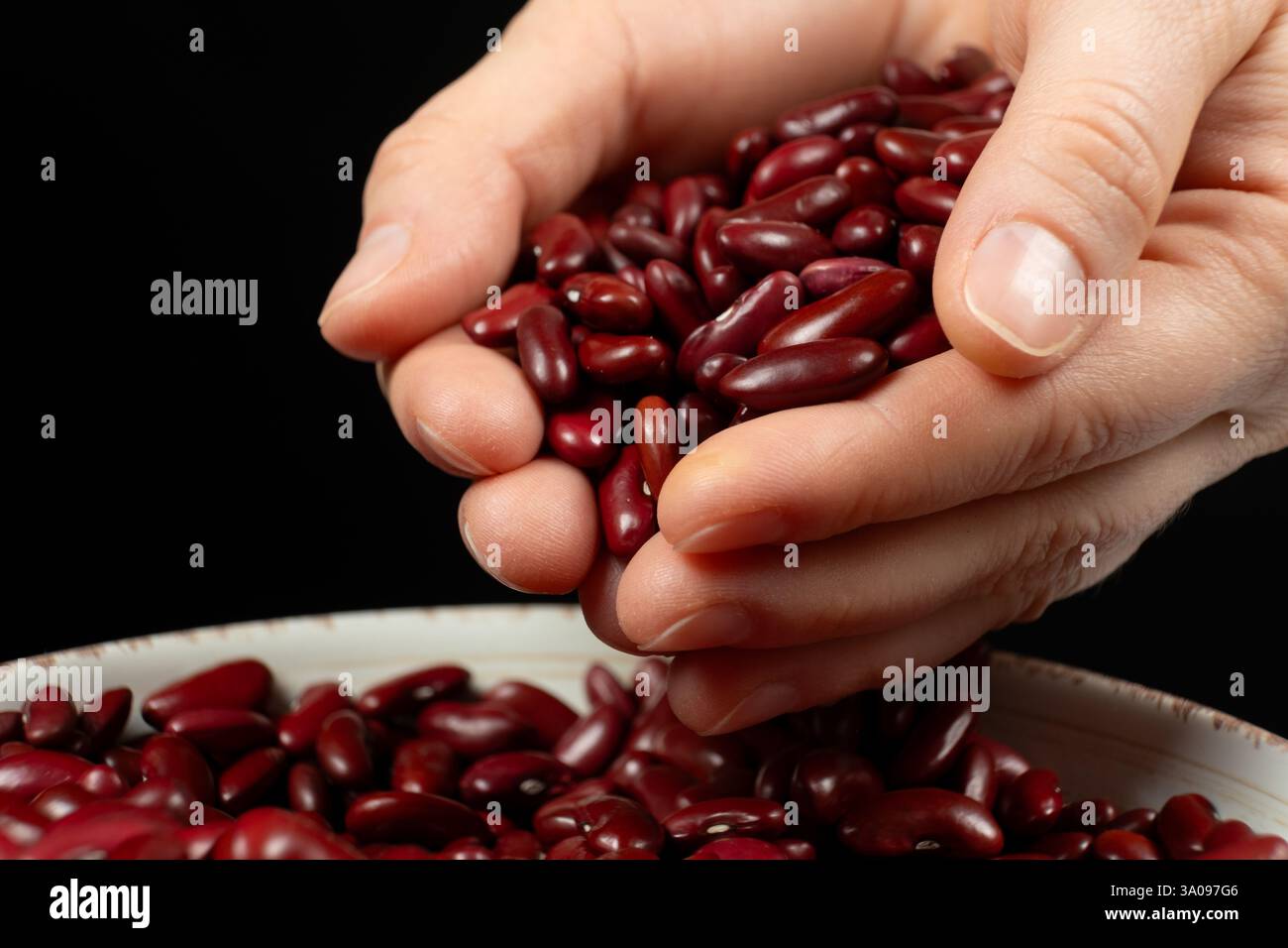 Mains versant des haricots rouges crus non cuits gros plan. Banque D'Images