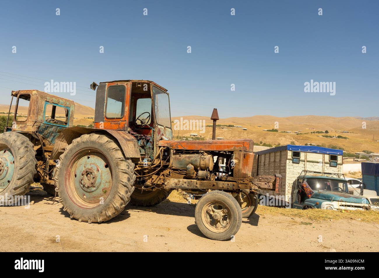 Un vieux tracteur est stationné dans un champ à côté d'une remorque Banque D'Images