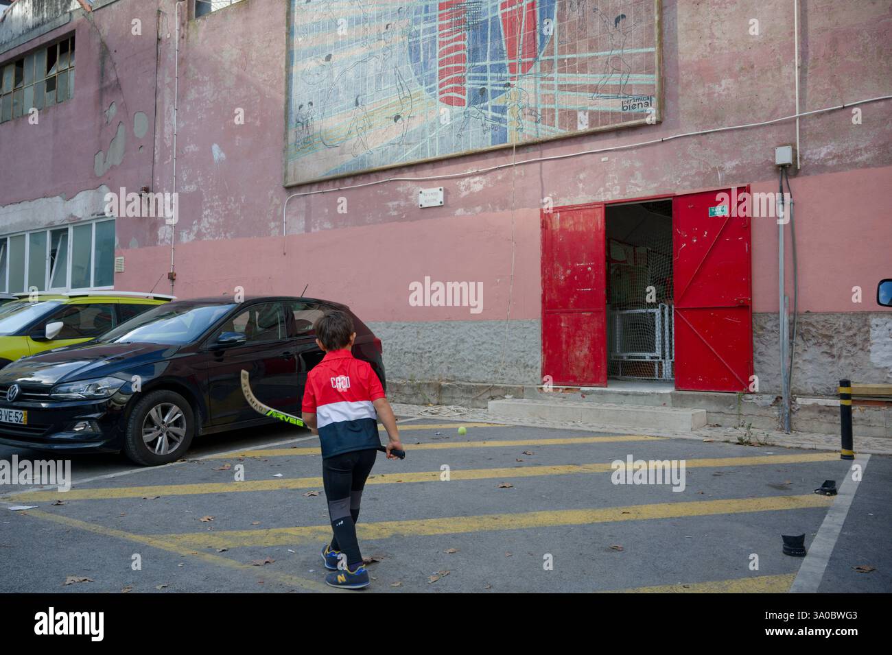 Un jeune joueur de hockey s’entraîne avec une balle de tennis et un bâton à l’entrée d’un centre de loisirs intérieur Banque D'Images