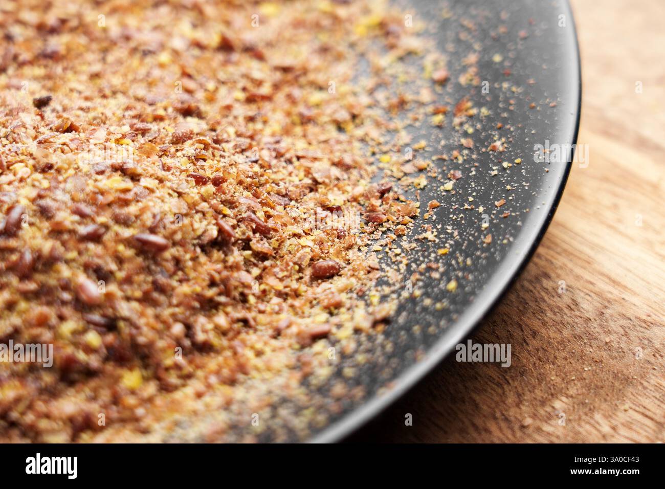 Graines de lin moulues dans une plaque noire sur une table en bois. Ingrédient biologique séché broyé. Brun superaliment sain nutritif. Banque D'Images