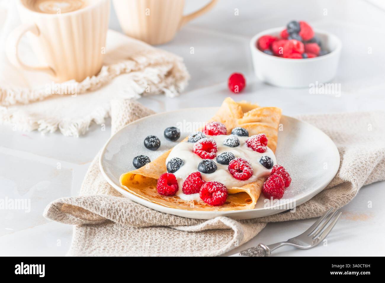 Crêpe avec fromage blanc ou fromage à la crème et rasperries et bleuets sur fond blanc Banque D'Images