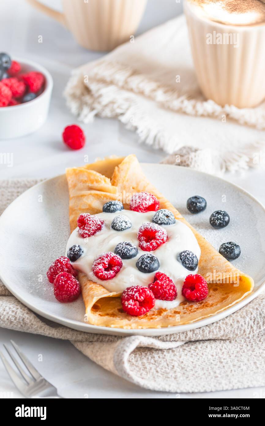 Crêpe avec fromage blanc ou fromage à la crème et rasperries et bleuets sur fond blanc, vertical Banque D'Images