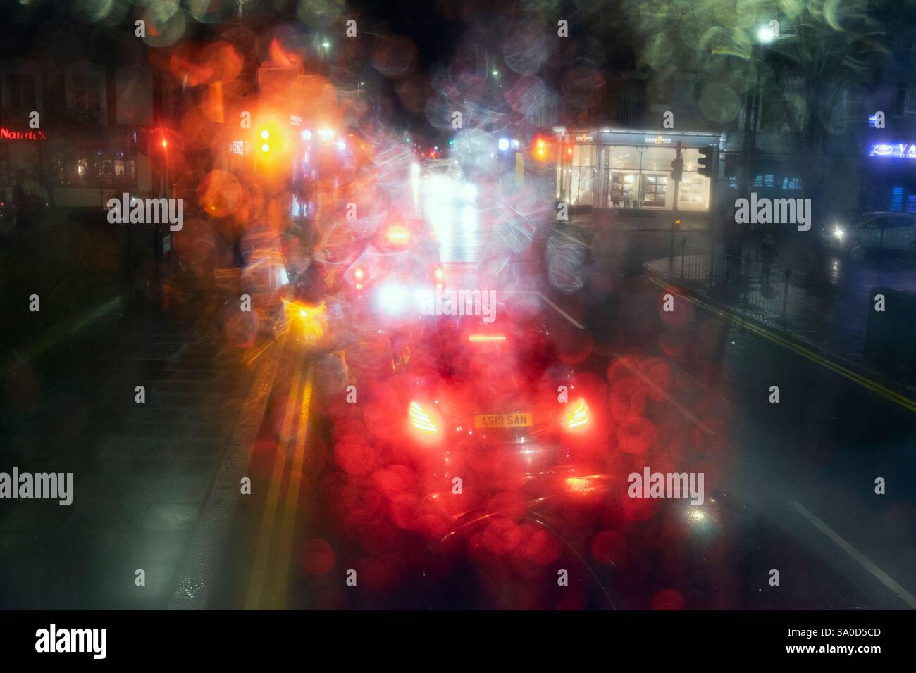 Vue sur un magasin coloré et des feux de circulation de voiture dans une rue la nuit à Londres vue à travers un bus à impériale à double étage dernier étage fenêtre de pluie Londres Royaume-Uni Banque D'Images