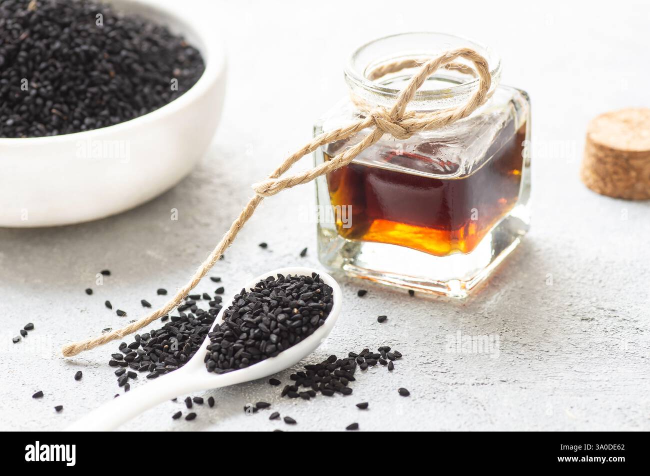 Bouteille en verre d'huile essentielle de graines de cumin noir, Nigella Sativa en cuillère sur fond rustique. Phytothérapie organique pour de nombreuses maladies, cumin noir Banque D'Images