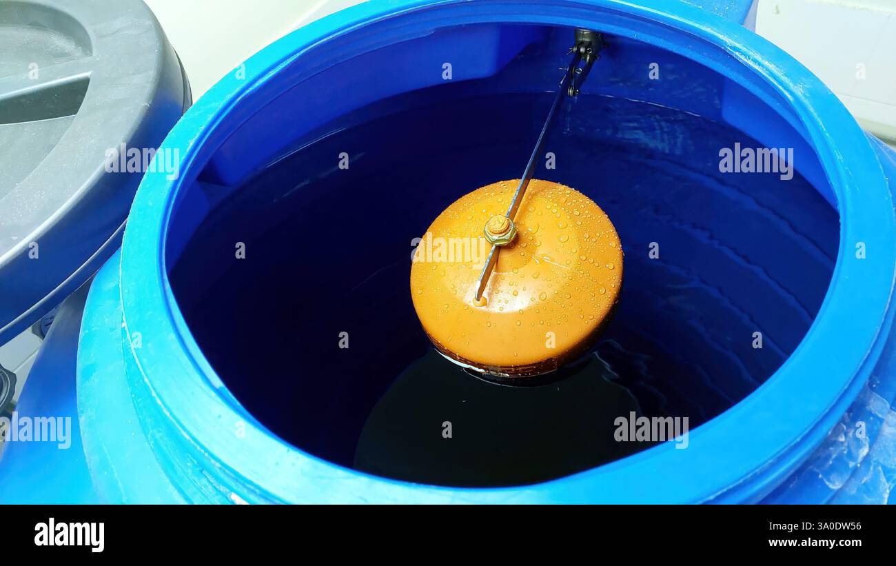 Un flotteur de vanne d'eau régule activement les niveaux d'eau dans un réservoir bleu, assurant une gestion efficace de l'eau et l'accessibilité dans une installation. Banque D'Images