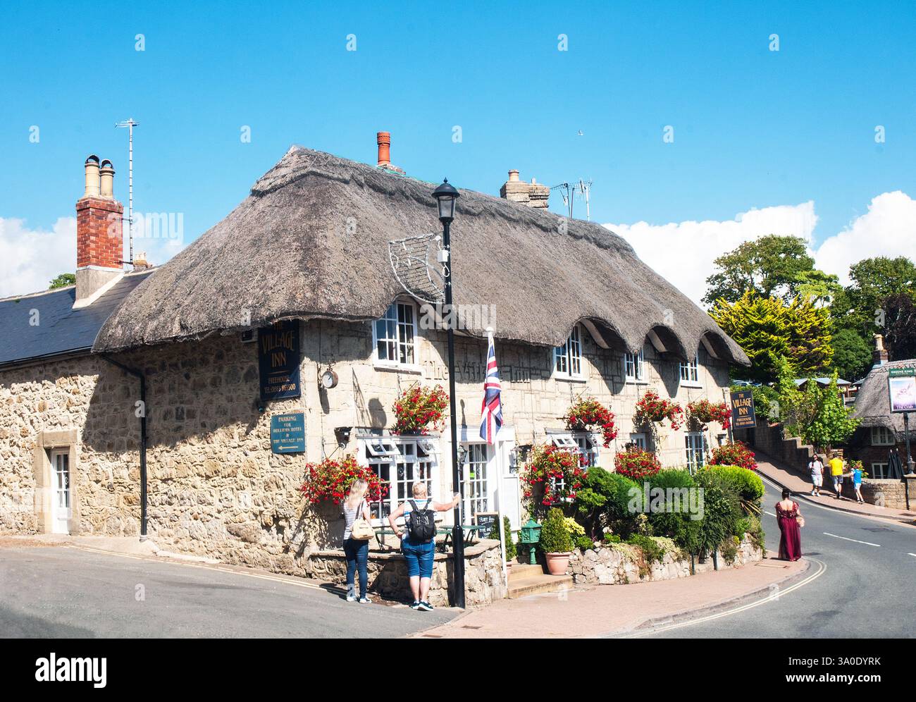 Les gens regardant le Village Inn avec un toit de chaume et beaucoup de paniers suspendus et un drapeau de l'Union Jack à l'extérieur dans Old Shanklin sur l'île de White Banque D'Images