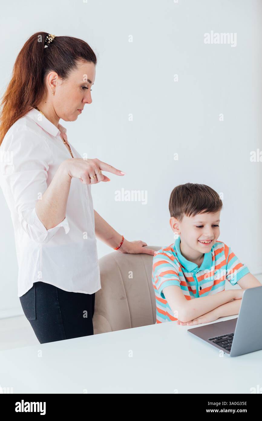 Une enseignante aide un garçon sur ordinateur portable à jouer en ligne à l'école Banque D'Images