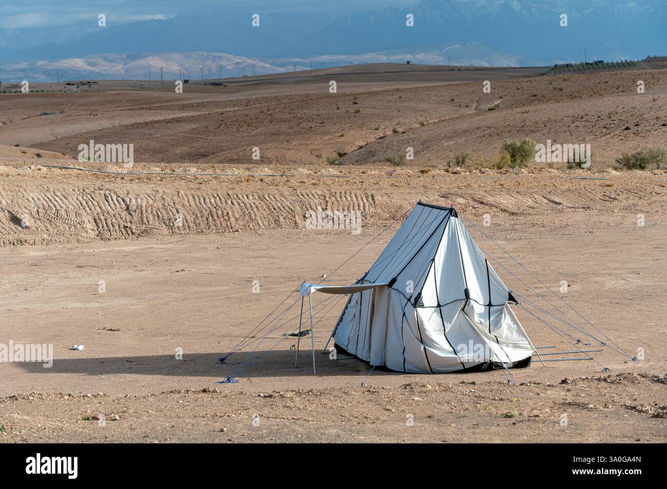 Une tente blanche se tient seule dans le désert marocain d'Agafay sous un ciel dégagé. Banque D'Images