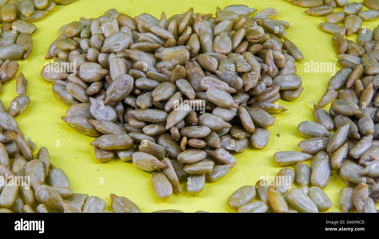 Les graines sont soigneusement disposées en forme de cœur sur une surface jaune vif, créant un design décoratif Banque D'Images