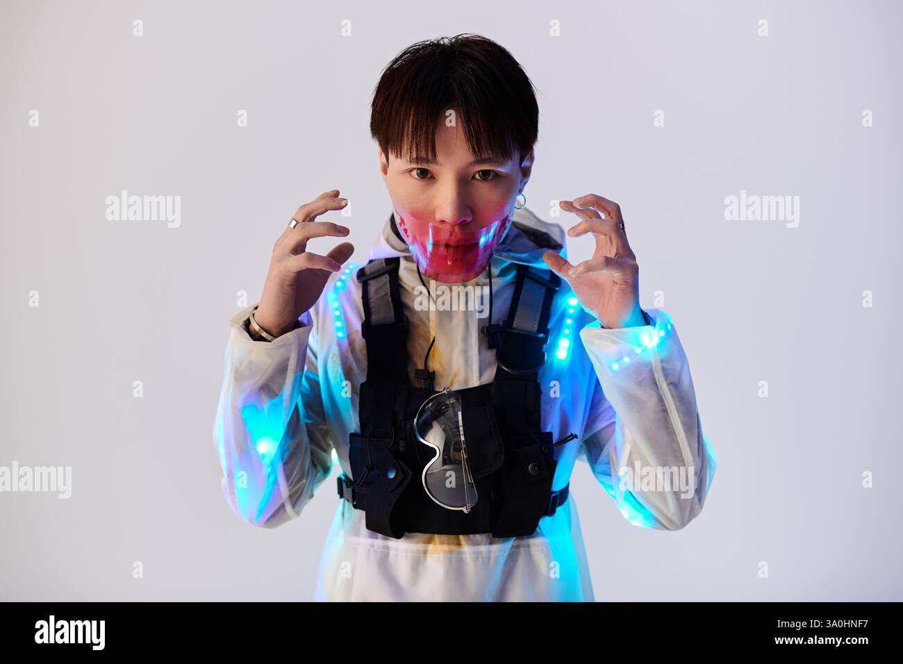 Jeune homme dans une tenue unique avec des éléments lumineux présente une ambiance artistique dans un cadre de studio. Banque D'Images