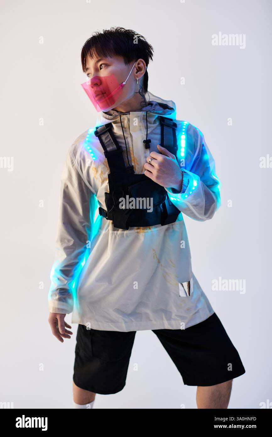 Jeune homme porte une tenue moderne avec des éléments lumineux, mettant l'accent sur le style urbain et la créativité. Banque D'Images