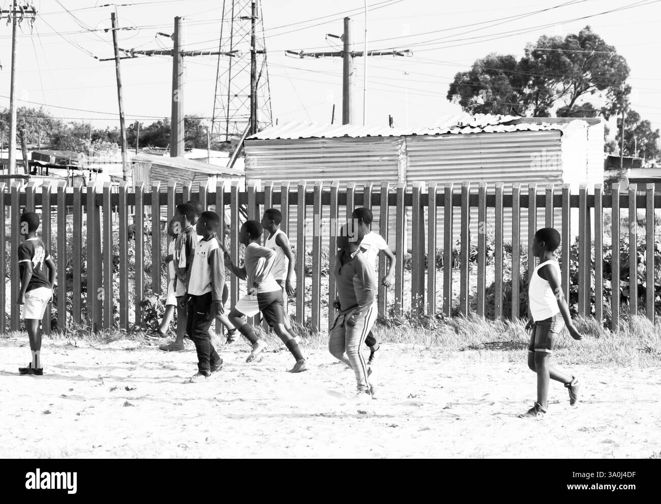 Enfants africains, enfants jouant au football devant des cabanes en étain dans un township du Cap, Afrique du Sud concept sport et loisirs vie quotidienne Banque D'Images