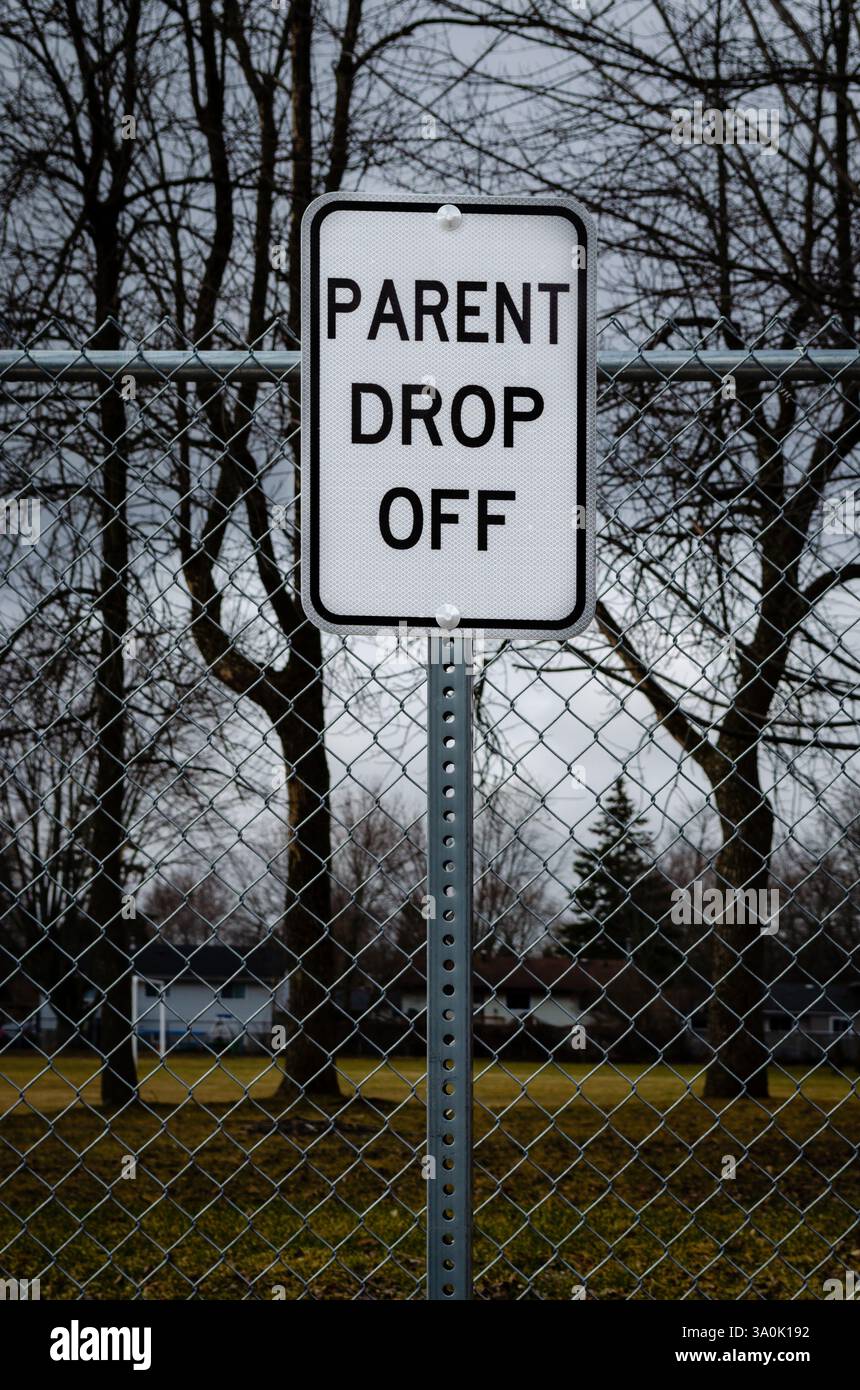 Panneau de dépôt des parents de la zone scolaire devant une clôture avec des arbres et des maisons en arrière-plan Banque D'Images Panneau de dépôt des parents de la zone scolaire devant une clôture avec des arbres et des maisons en arrière-plan Banque D'Images