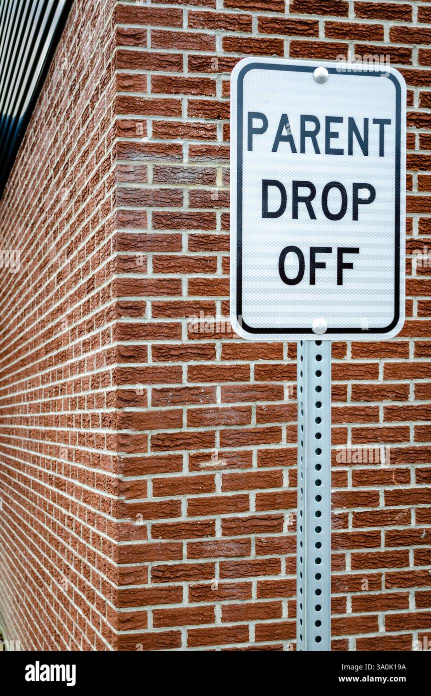 Panneau de dépôt des parents de la zone scolaire à côté d'un mur extérieur en briques marron Banque D'Images Panneau de dépôt des parents de la zone scolaire à côté d'un mur extérieur en briques marron Banque D'Images