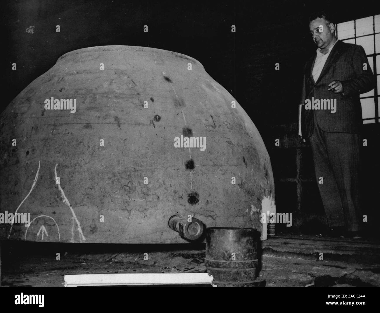 La bathysphère du Professeur Piccard -- ingénieur Elio Sebastiani, l'un des planificateurs de la bathysphère, près du sommet de la bathysphère dans les ateliers de Terni, Italie. Photo reçue à Londres aujourd'hui 29 novembre. Travaux sur la bathysphère, une sorte de sphère pour l'observation et l'étude des eaux profondes, pour le scientifique d'origine suisse, le professeur Auguste Piccard procède aux travaux métallurgiques de Terni, en Italie. Une fois la bathysphère terminée, le Professeur Piccard tentera de battre le record du Professeur Beebe lorsqu'il descendra pour des observations au large de l'île de Ponza, dans la baie de Naples. 29 novembre 1952. (Photo Banque D'Images