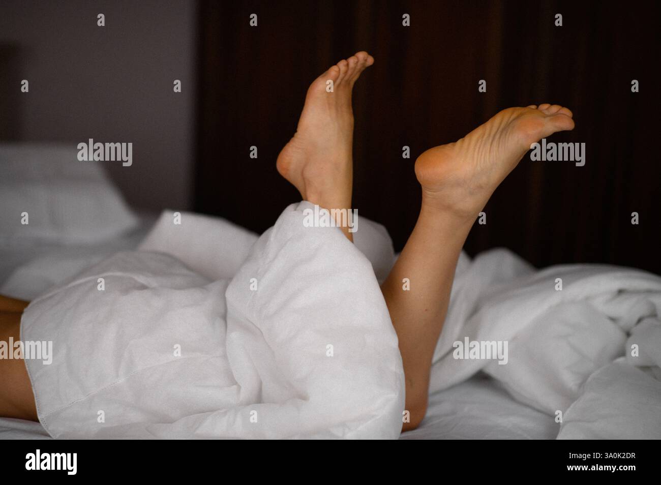 femme jambes le matin sous la couverture Banque D'Images