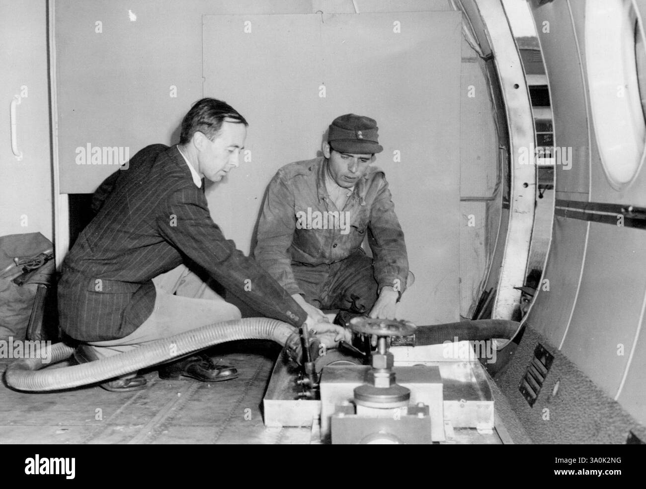 Don Bennett apporte l'avion du centenaire d'Airleft -- le vice-maréchal de l'air Donald Bennett (au premier plan) supervise l'accouplement du tuyau de carburant pour le déchargement de la cargaison à l'aérodrome de Gatgow, Berlin. Le vice-maréchal de l'air Donald Bennett, ancien Pathfinder et chef de British South American Airways, pilote un avion Tudor V qui arrive à l'aéroport de Gatow le 100e jour du pont aérien de Berlin. Le Tudor transportait 2 600 gallons d'huile diesel dont le besoin était urgent. 04 octobre 1948. Banque D'Images