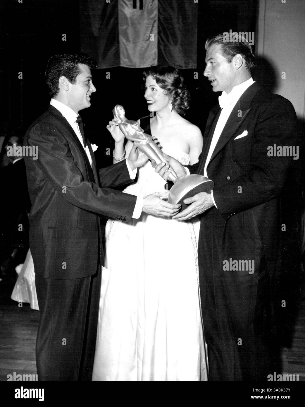Autorisation accordée pour la reproduction de journaux et de magazines. Tony Curtis, la jeune étoile montante d'Universal-International, reçoit une statuette présentée par Arlene Dahl et Lex Barker au nom de l'association de presse étrangère d'Hollywood qui a honoré Curtis comme l'un des six nouveaux arrivants à l'écran « dont les réalisations les ont marqués pour la célébrité internationale dans un avenir proche ». 16 avril 1952. (Photo par Universal - International). Banque D'Images