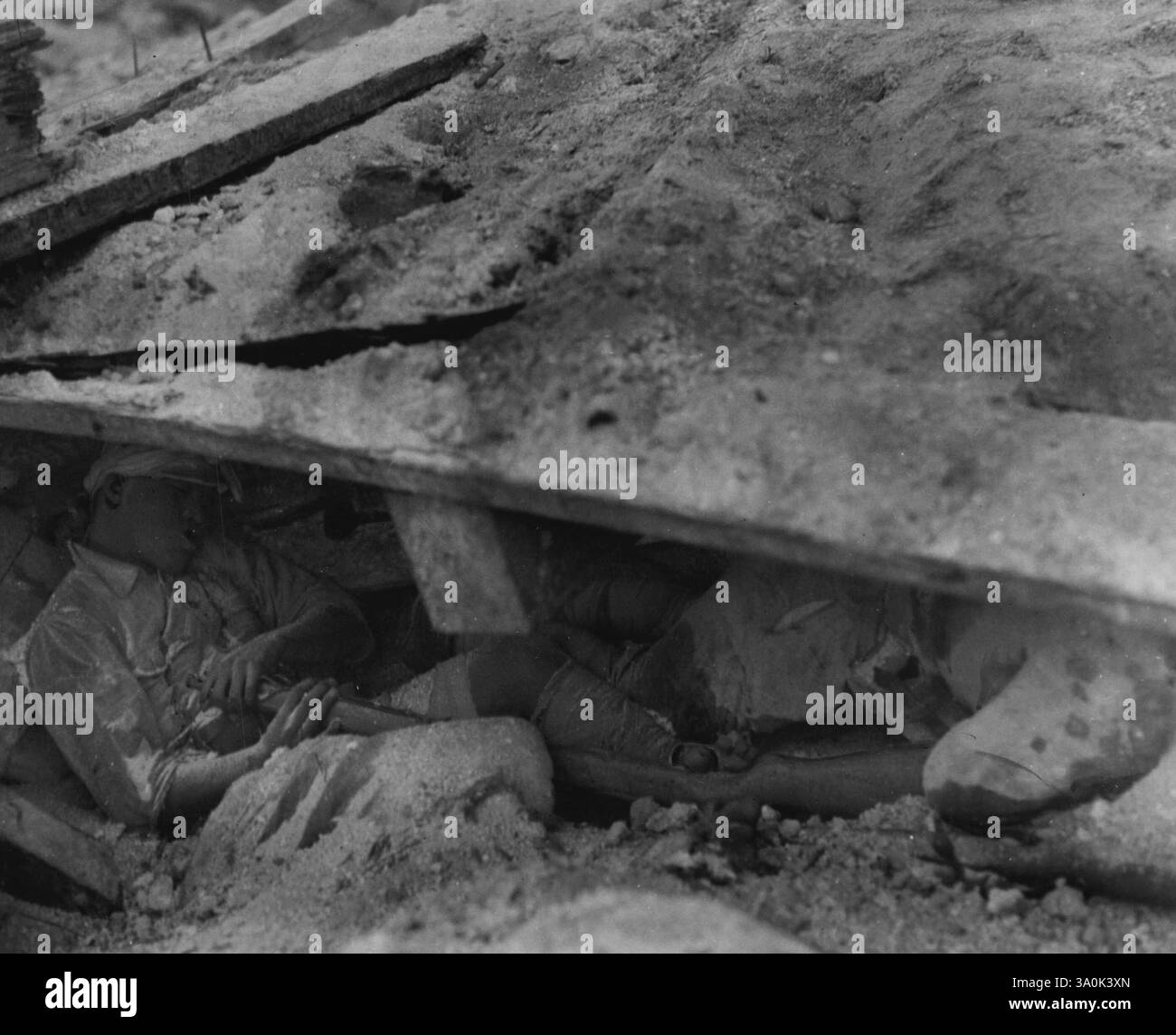 Hara-Kiri à Tarawa -- ces Japs qui ont eu recours au hara-kiri pendant la conquête de Tarawa par les Marines dans les Gilberts, ne sont pas tous tombés par l'épée traditionnelle Bamaurai. Ceci est une image de mort auto-infligée peu de temps après que les Japonais se soient suicidés en poussant son gros orteil contre la gâchette de son fusil, avec le museau contre sa poitrine. Notez que l'orteil du Jap appuie toujours sur la gâchette. Un deuxième Jap mort peut être vu sous le toit de la fosse démolie. 20 décembre 1943. (Photo de la photographie officielle des cultures marines des États-Unis). Banque D'Images