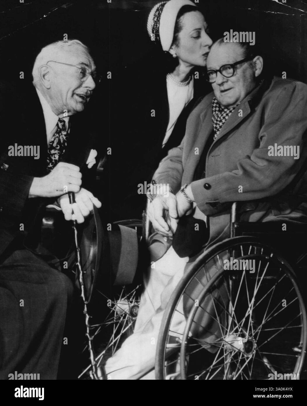 Réunion d'audience -- Lionel Barrymore, acteur de cinéma confiné à un fauteuil roulant par paralysie, reçoit un baiser d'Helene Costello alors qu'il quitte le tribunal aujourd'hui après avoir témoigné dans le procès de Mlle Costello pour la garde de sa fille Diedre, âgée de six ans. Dire au revoir à gauche est son ami de longue date, Maurice Costello, qui témoignera plus tard. Barrymore a témoigné qu'il avait prêté à Mlle Costello une somme de 1 000 $ en 1943 pour une série d'opérations, contredisant le témoignage de son mari, Lee le Blanc. 29 décembre 1947. (Photo de AP Wirephoto). Banque D'Images