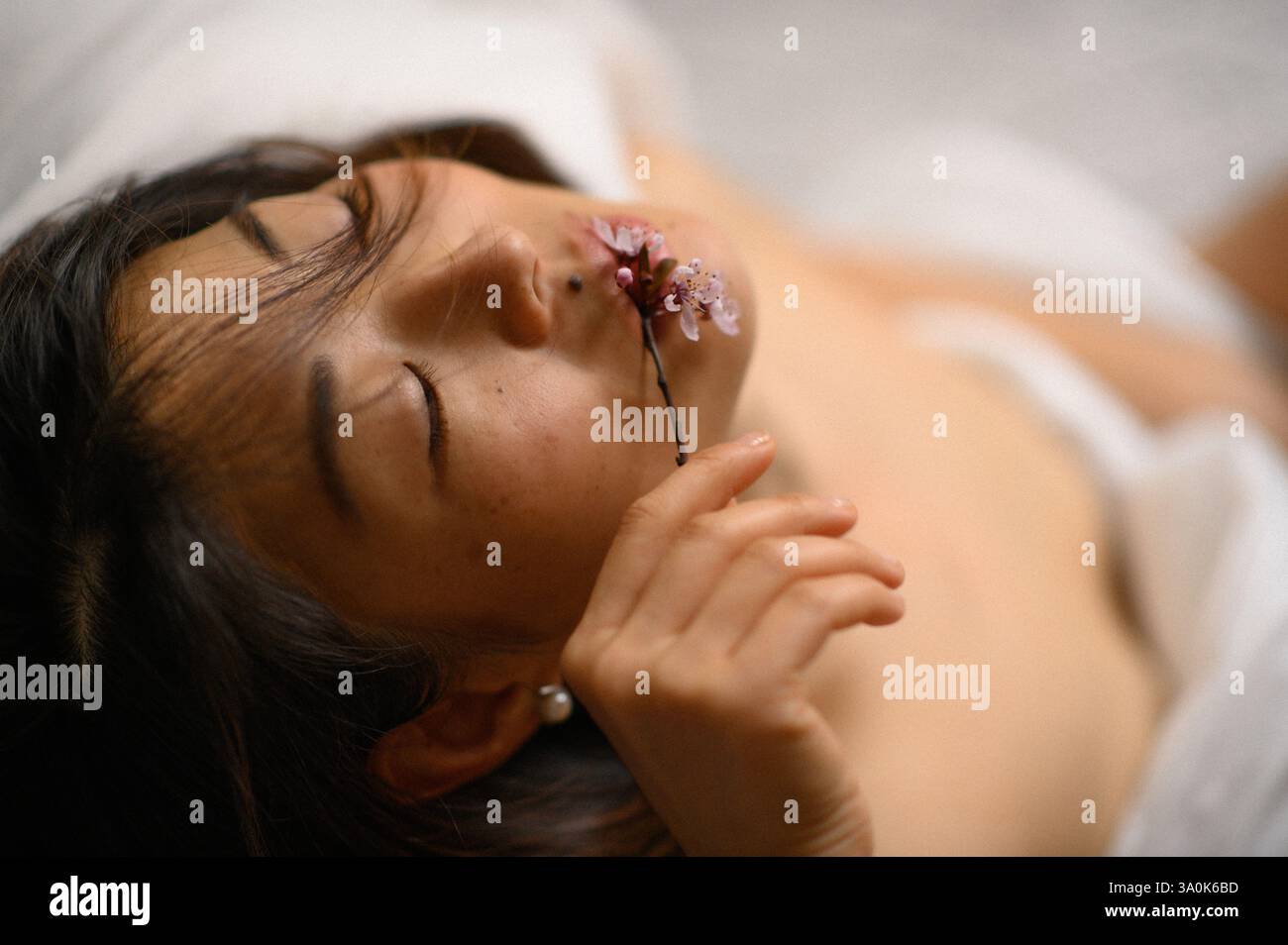 femme asiatique avec fleur rose près de son visage Banque D'Images