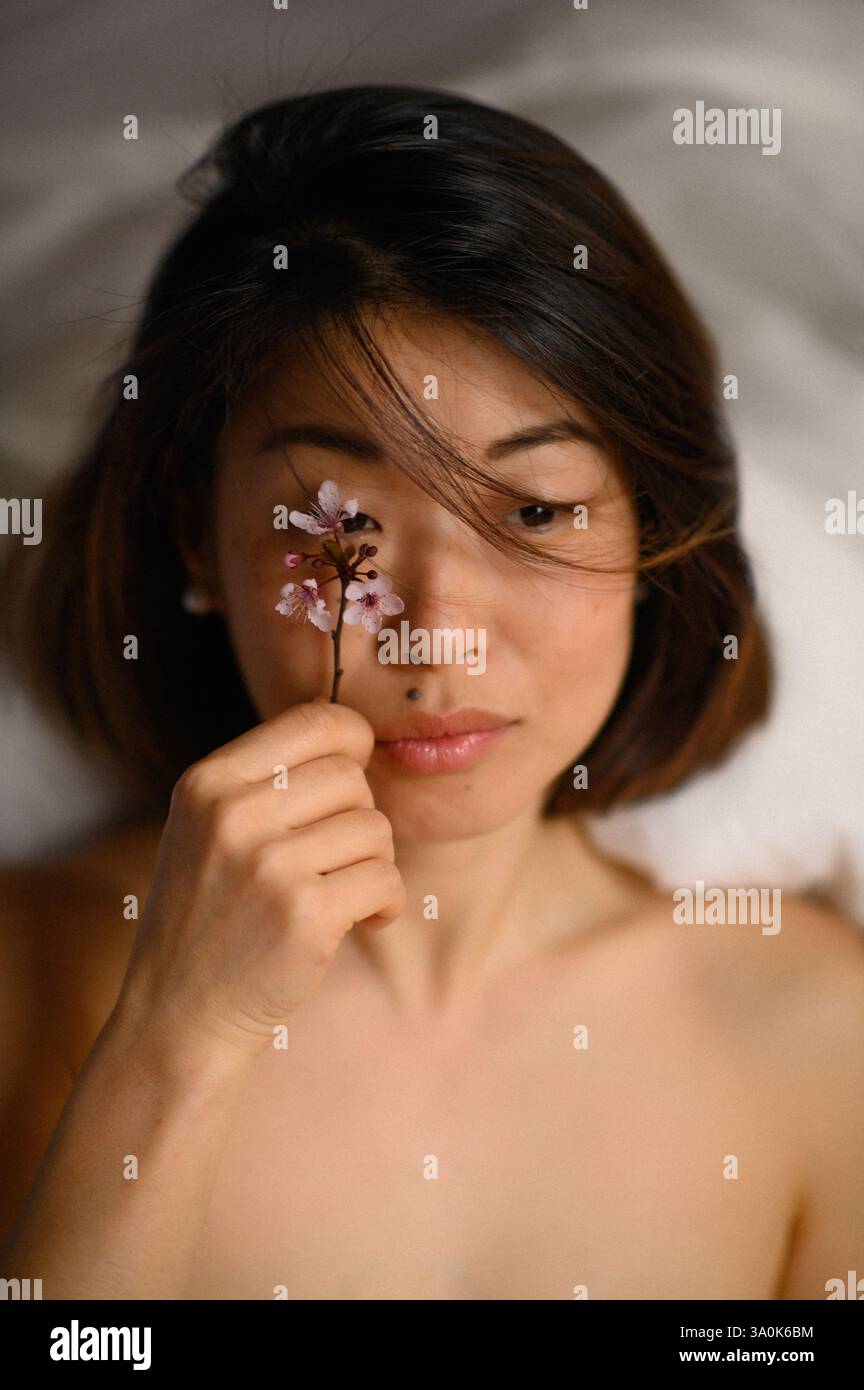 femme asiatique avec fleur rose près de son visage Banque D'Images