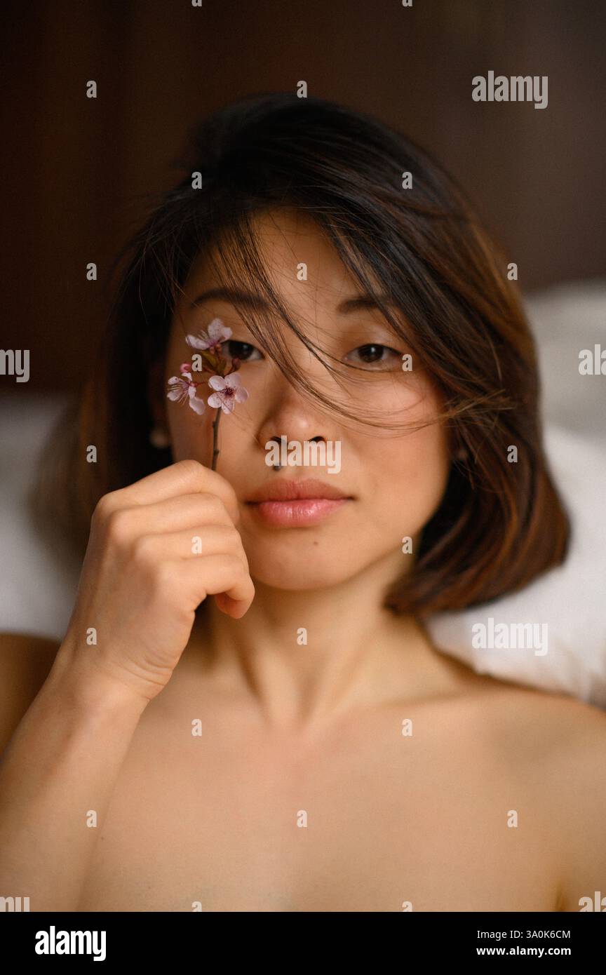 femme asiatique avec fleur rose près de son visage Banque D'Images