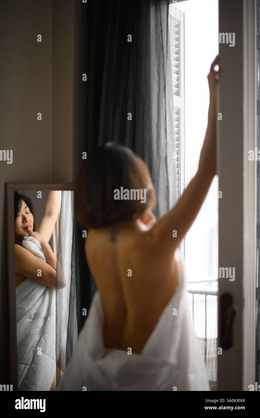 Le miroir reflète le visage d’une jeune femme, son expression douce et contemplative alors qu’elle regarde sa propre image. Banque D'Images