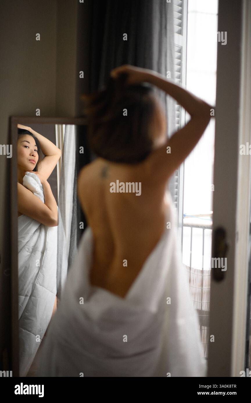 Le miroir reflète le visage d’une jeune femme, son expression douce et contemplative alors qu’elle regarde sa propre image. Banque D'Images