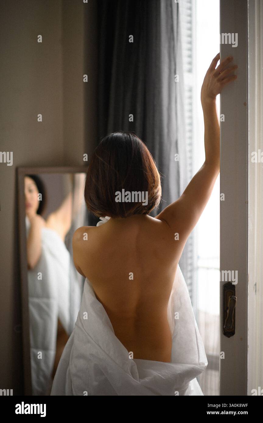 Le miroir reflète le visage d’une jeune femme, son expression douce et contemplative alors qu’elle regarde sa propre image. Banque D'Images