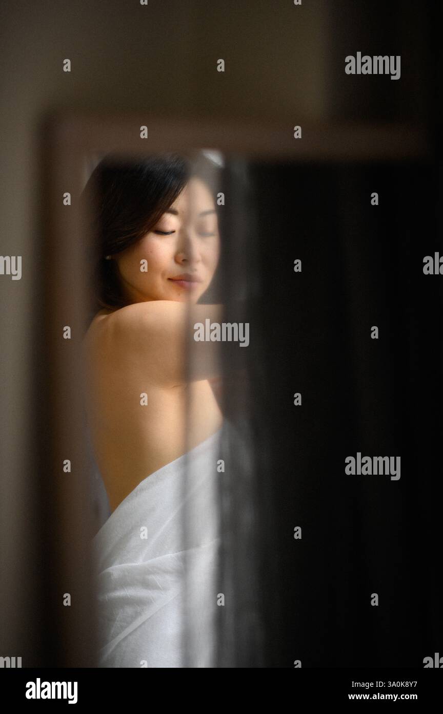 Le miroir reflète le visage d’une jeune femme, son expression douce et contemplative alors qu’elle regarde sa propre image. Banque D'Images