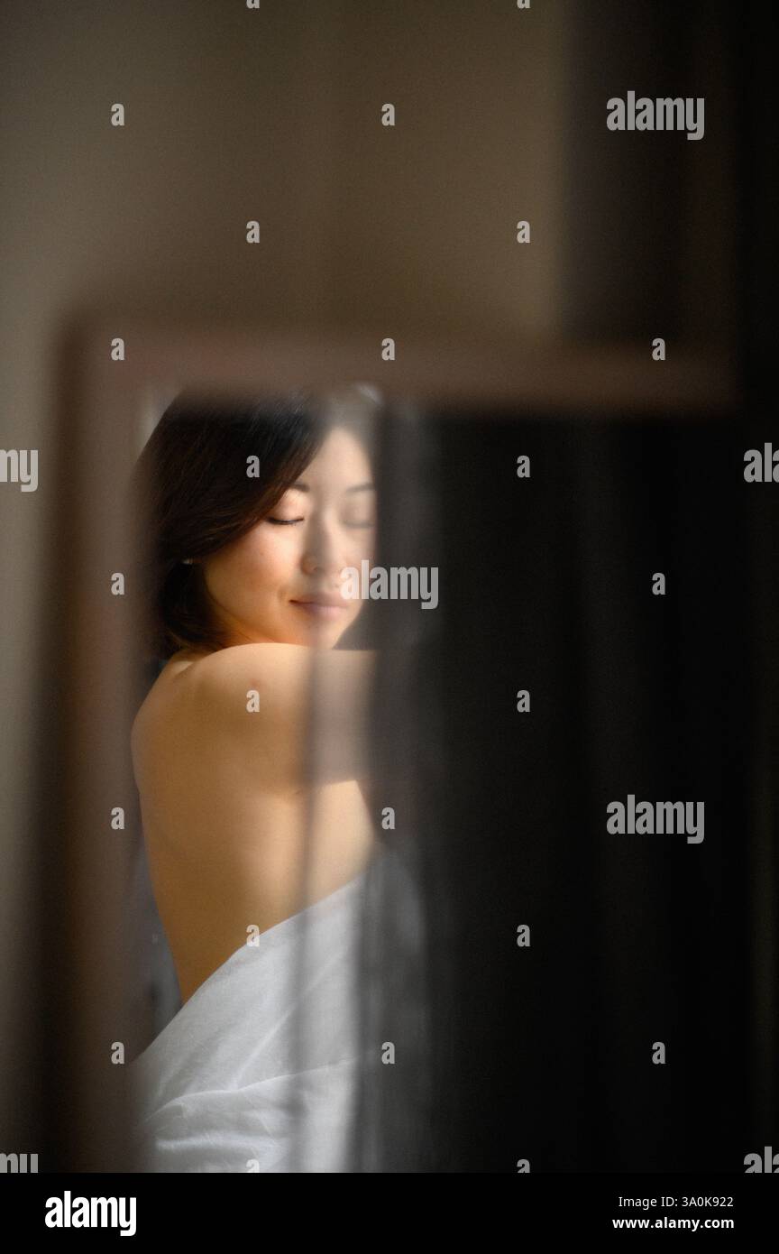 Le miroir reflète le visage d’une jeune femme, son expression douce et contemplative alors qu’elle regarde sa propre image. Banque D'Images