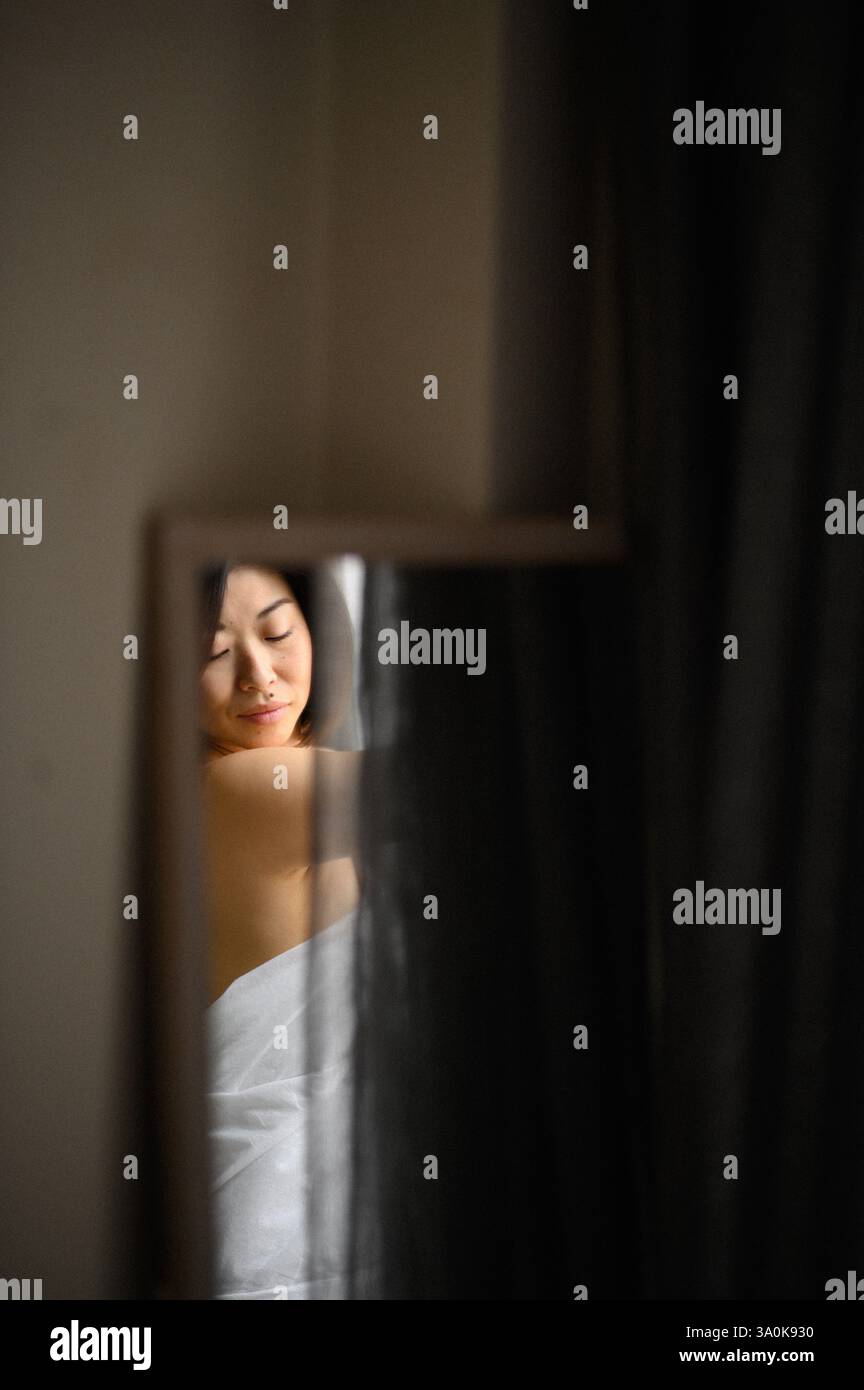 Le miroir reflète le visage d’une jeune femme, son expression douce et contemplative alors qu’elle regarde sa propre image. Banque D'Images