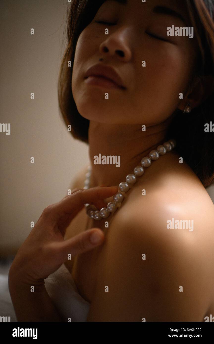 Une dame gracieuse ornée de perles délicates, ses yeux reflétant une sophistication tranquille. Banque D'Images