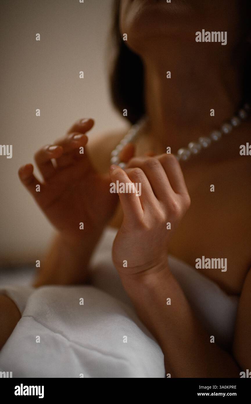 Une dame gracieuse ornée de perles délicates, ses yeux reflétant une sophistication tranquille. Banque D'Images