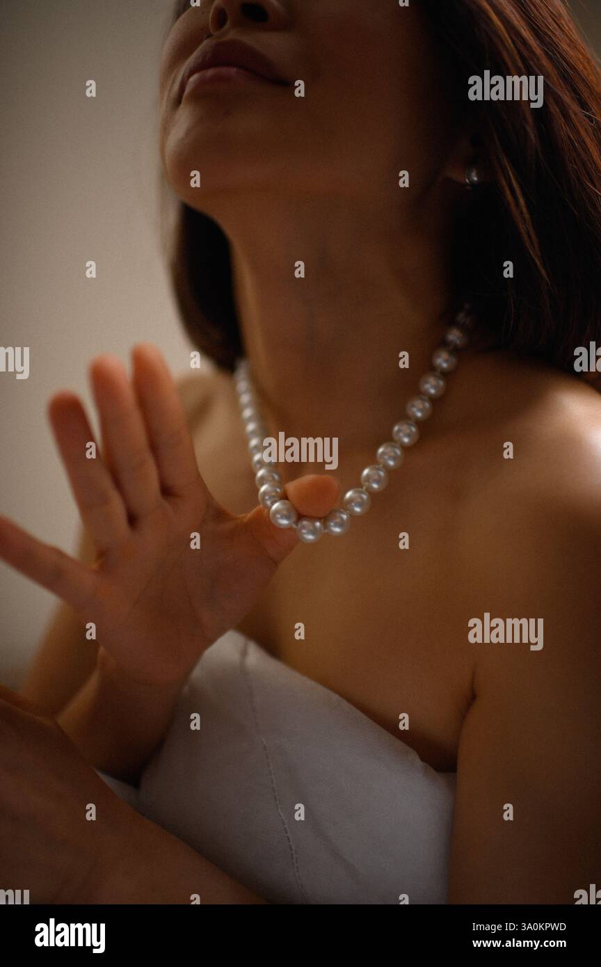 Une dame gracieuse ornée de perles délicates, ses yeux reflétant une sophistication tranquille. Banque D'Images