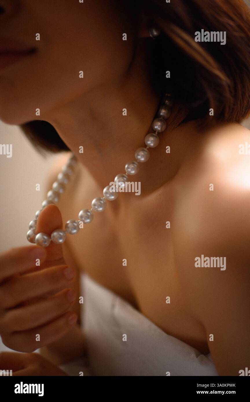 Une dame gracieuse ornée de perles délicates, ses yeux reflétant une sophistication tranquille. Banque D'Images