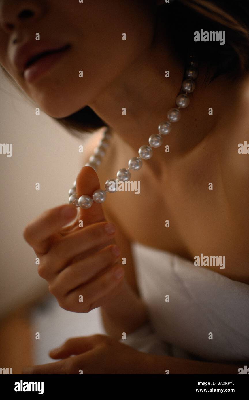 Une dame gracieuse ornée de perles délicates, ses yeux reflétant une sophistication tranquille. Banque D'Images