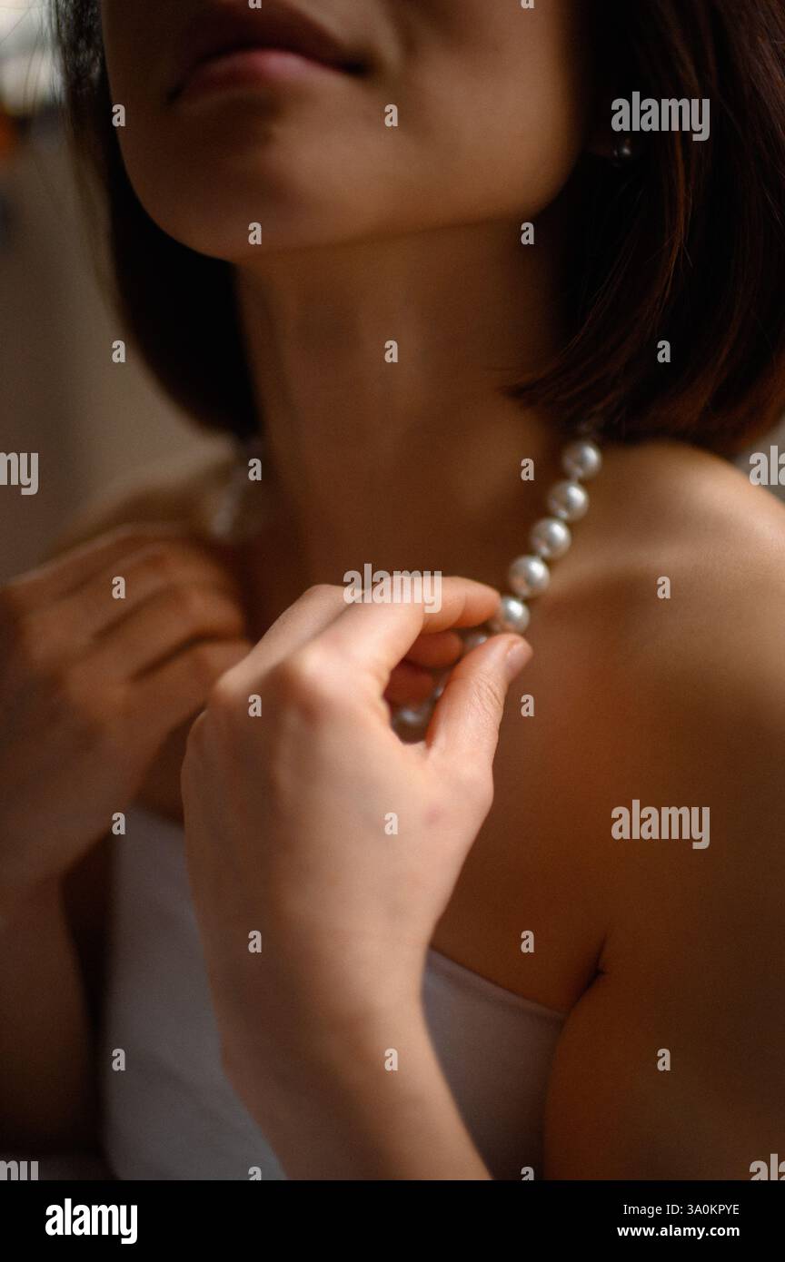 Une dame gracieuse ornée de perles délicates, ses yeux reflétant une sophistication tranquille. Banque D'Images