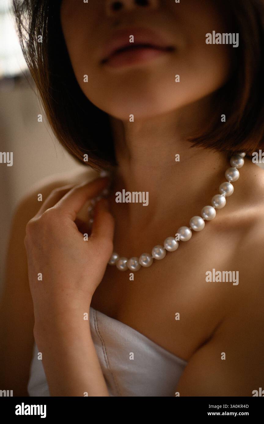 Un portrait d'une femme avec une boucle d'oreille en perles et un collier, exsudant une beauté intemporelle. Banque D'Images