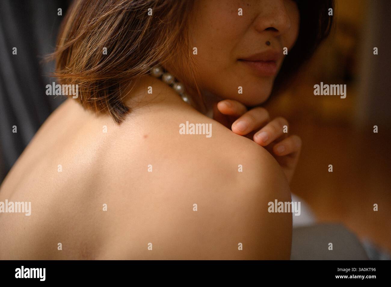 Une jeune femme regarde doucement, portant une élégante boucle d'oreille en perles et un collier assorti. Banque D'Images