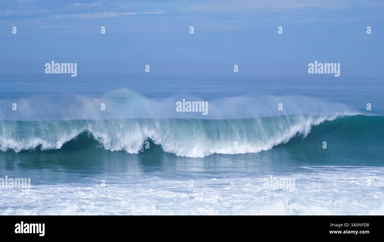 Tidal Drama : vague s'écrasant sous un ciel dégagé. Californie, Comté de San Mateo, rouleau de la côte Pacifique Banque D'Images