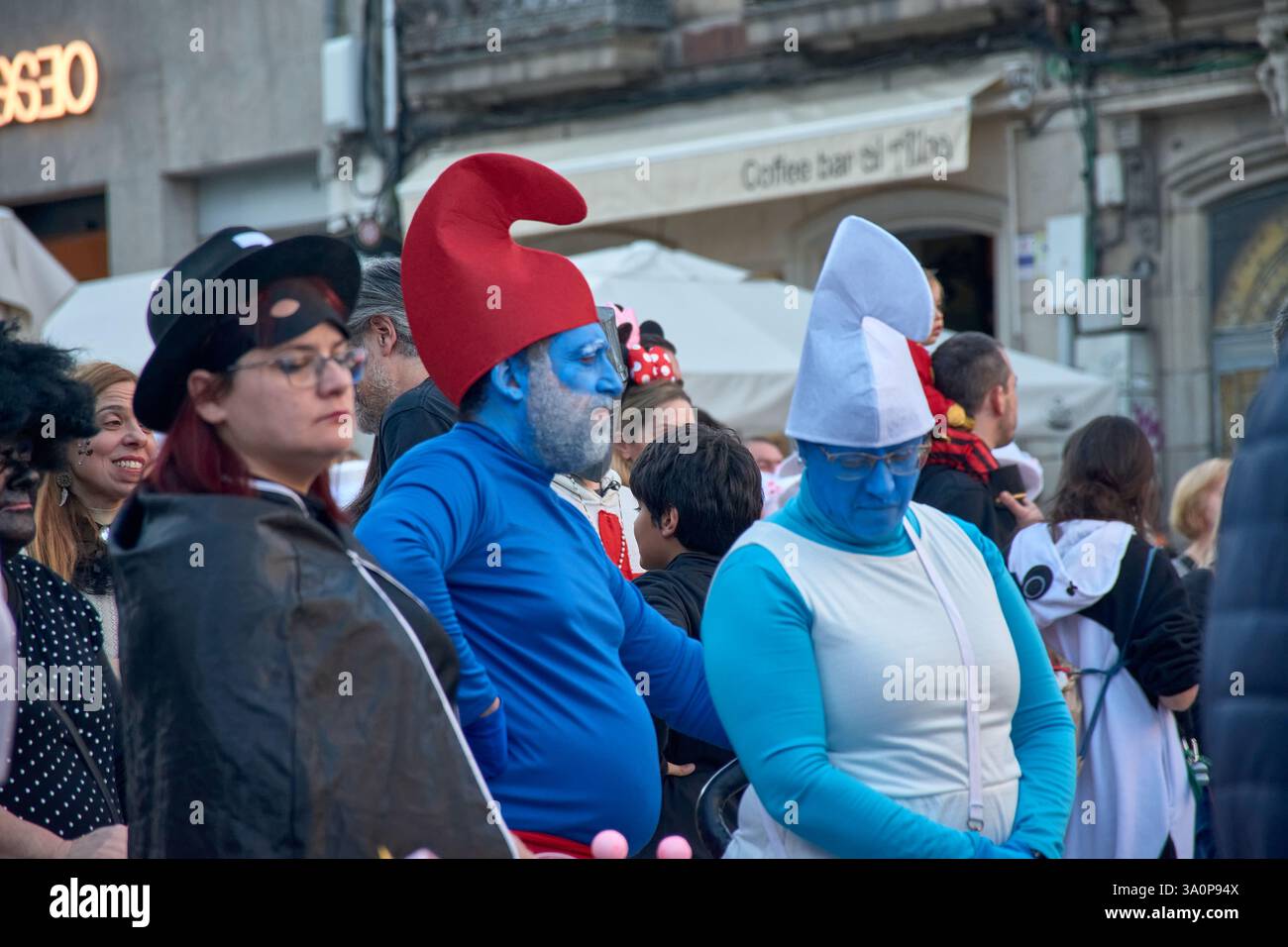 Vigo,Pontevedra,Espagne;4 mars 2025 : Un homme habillé en Schtroumpf se tient parmi la foule au vibrant Carnaval de Vigo en Espagne. Son visage est peint complet Banque D'Images