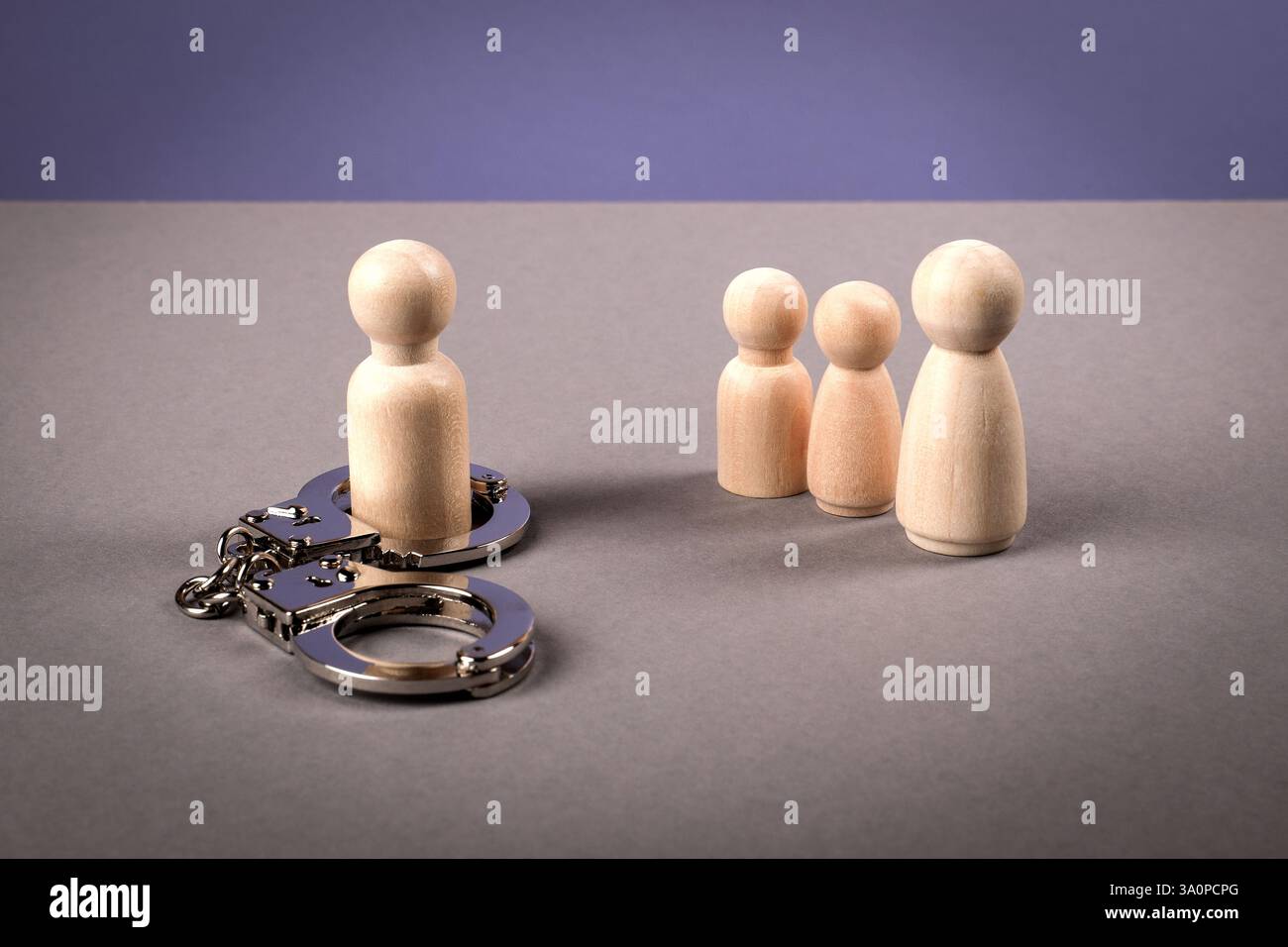 Notion d'emprisonnement et de séparation familiale. Figurines en bois avec menottes Banque D'Images