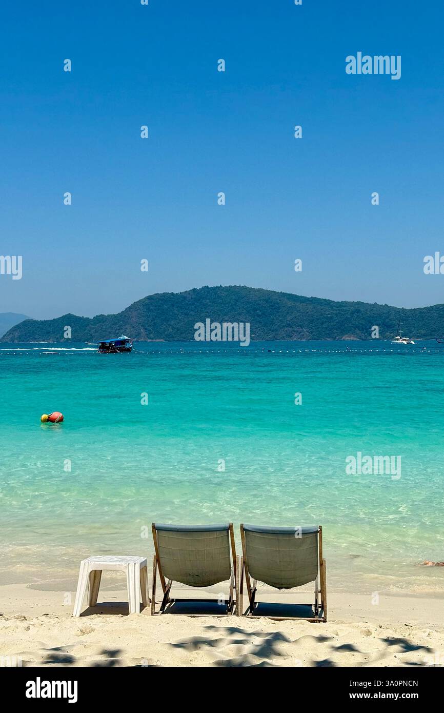 Eaux turquoise et chaises longues dans un paradis tropical deux chaises longues en bois sont assis sur une plage de sable immaculée, offrant une vue imprenable sur le - Image de stock capturée avec un smartphone