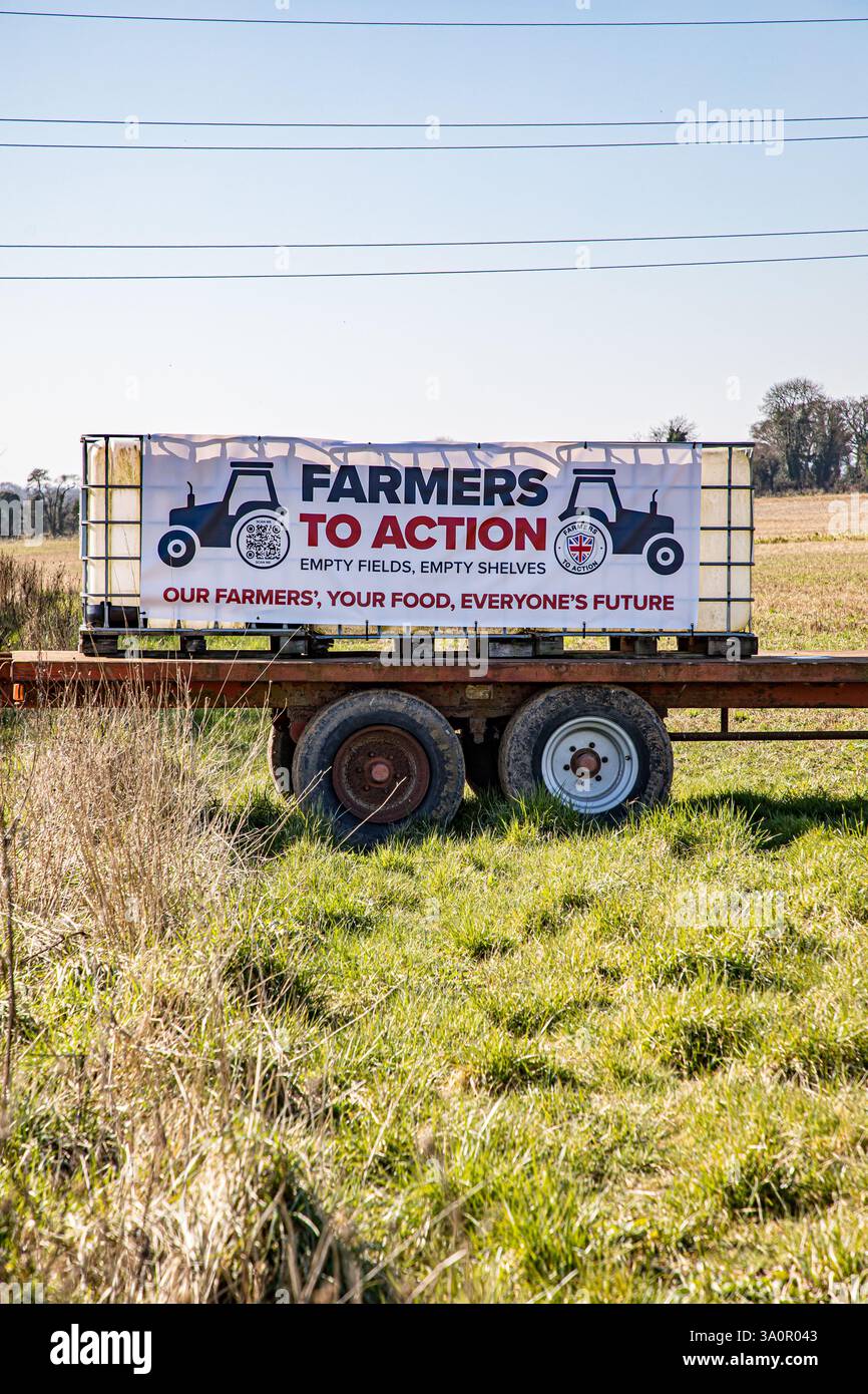 FERMIERS À LA bannière D'ACTION attachée à des transporteurs d'eau sur une remorque agricole dans un champ arable Banque D'Images