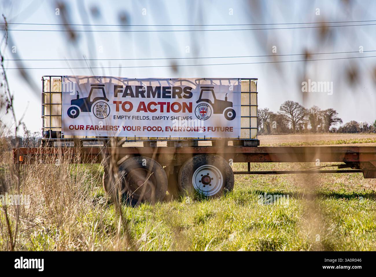 FERMIERS À LA bannière D'ACTION attachée à des transporteurs d'eau sur une remorque agricole dans un champ arable Banque D'Images