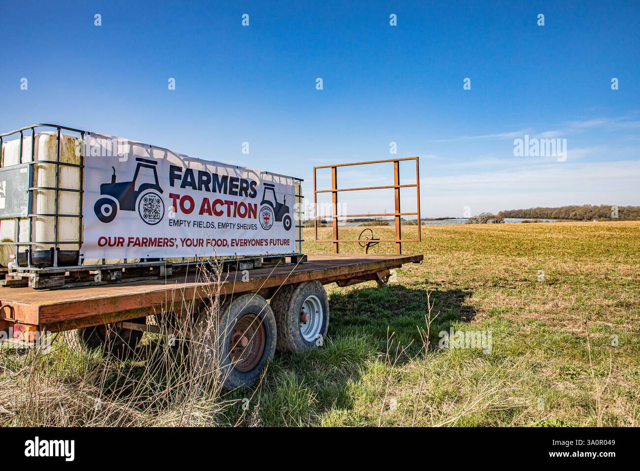 FERMIERS À LA bannière D'ACTION attachée à des transporteurs d'eau sur une remorque agricole dans un champ arable Banque D'Images
